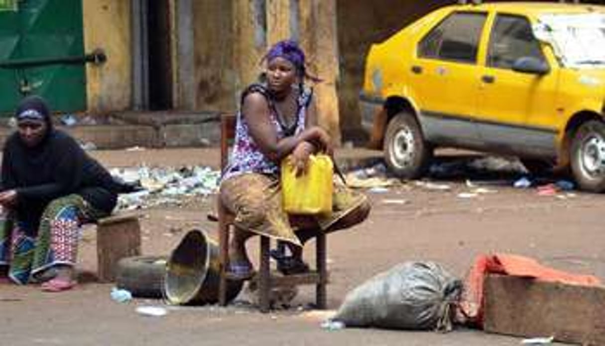 Guinéenne assise avec un bidon d’eau vide dans le quartier Bambeto à Conakry. © AFP