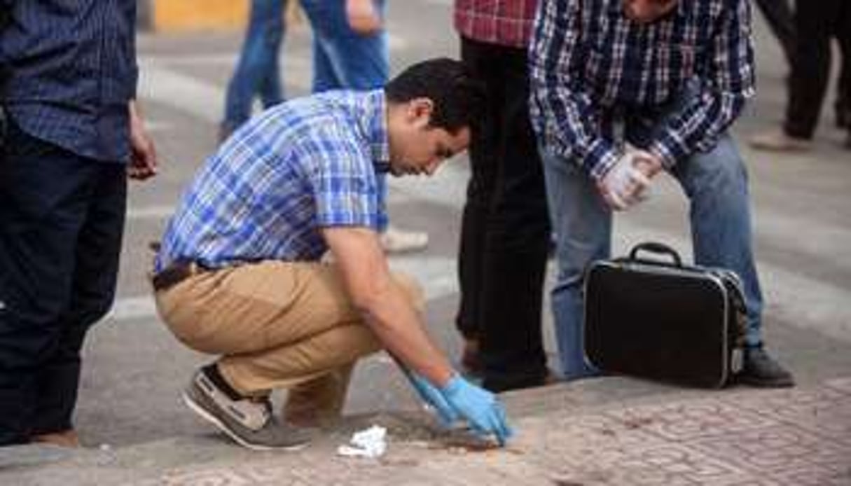 Des enquêteurs sur le lieu de l’explosion d’une bombe le 15 avril 2014 au Caire. © AFP