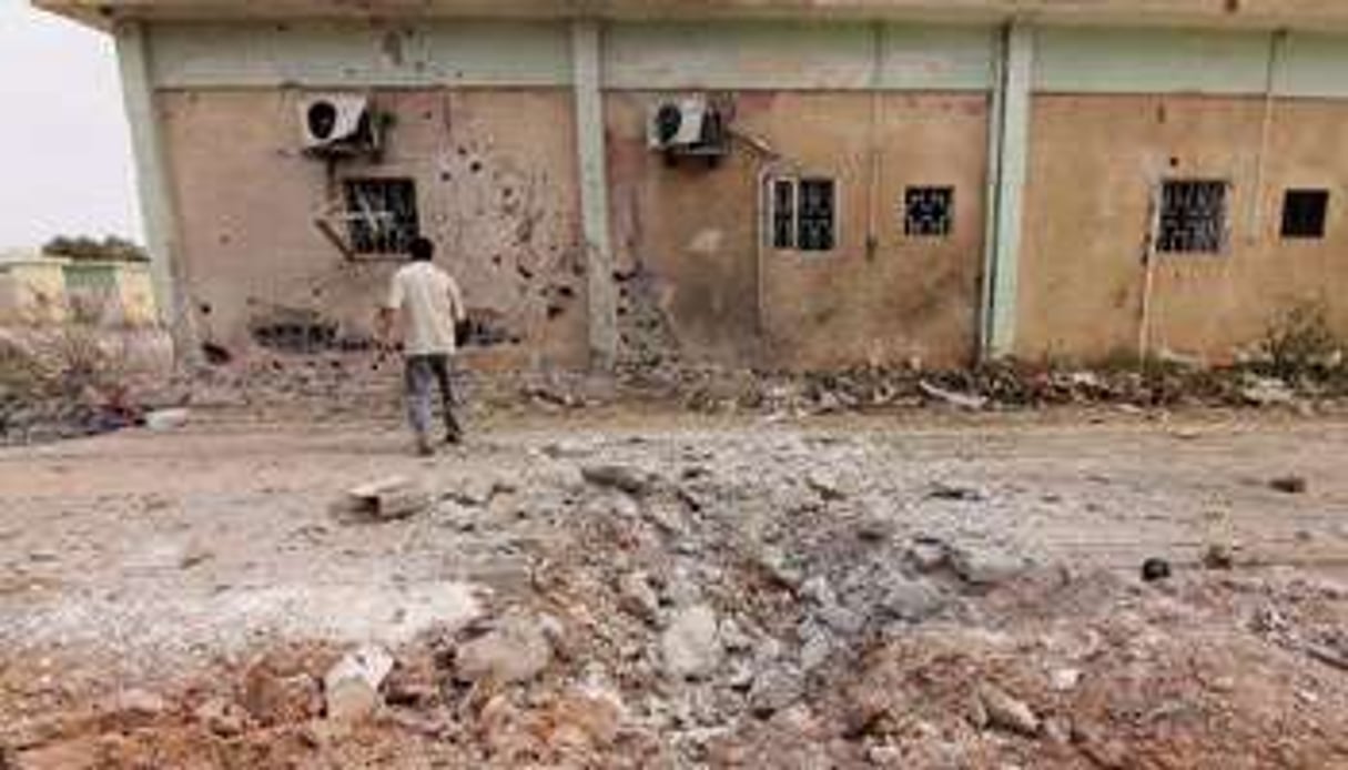 Un journaliste regarde le bâtiment endommagé d’un camp d’une brigade islamiste. © AFP