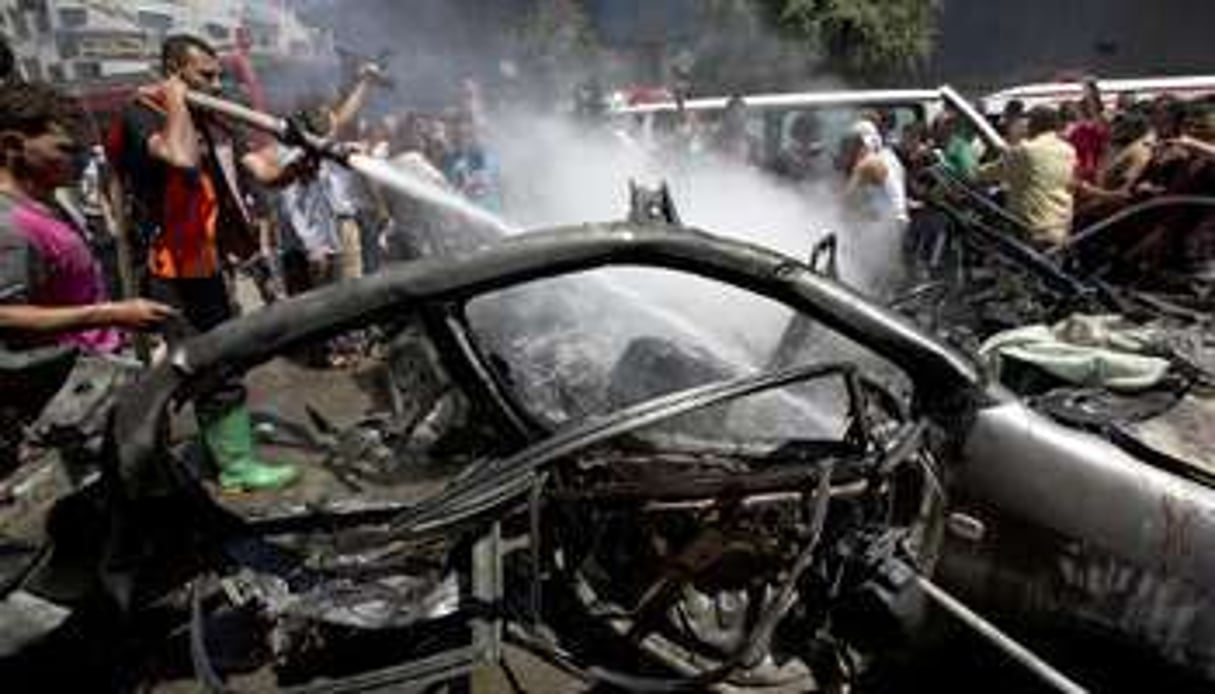 Des pompiers éteignent le feu dans un véhicule après une frappe aérienne israélienne. © AFP