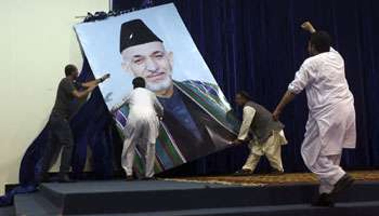 Des partisans d’Abdullah Abdullah décrochent un portrait de Hamid Karzaï, le président sortant. © Omar Sobhani/Reuters