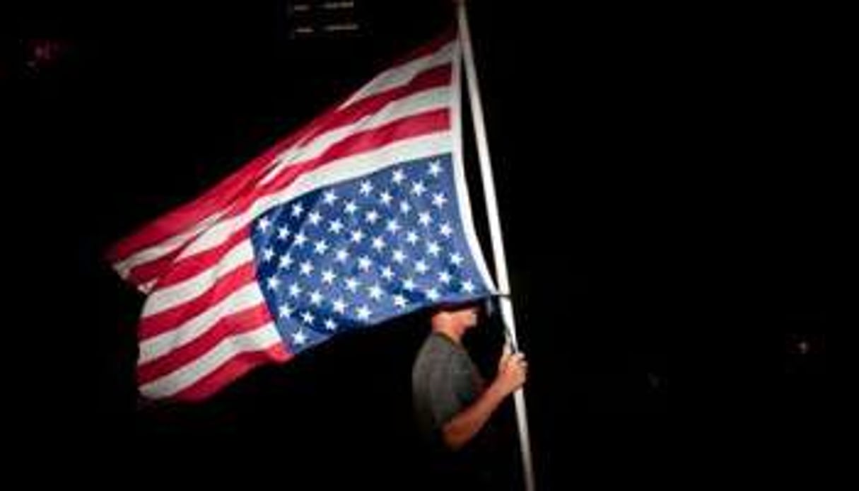 Un homme portant le drapeau américain. © AFP