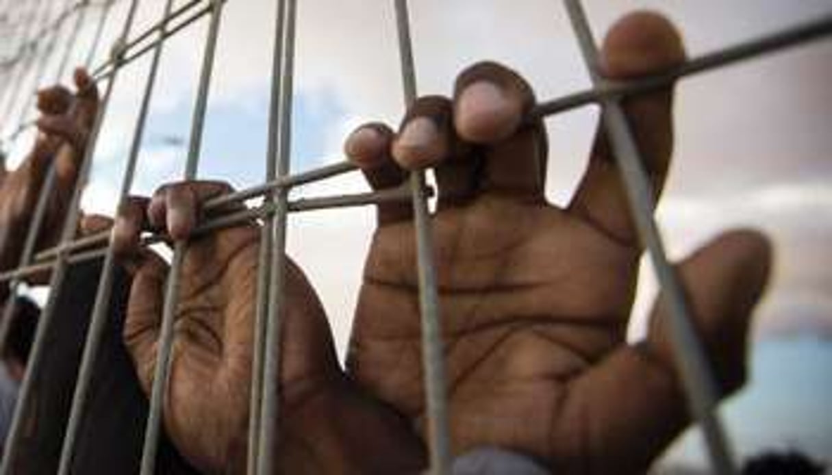 Des mains derrière un grillage dans un centre de détention. © AFP