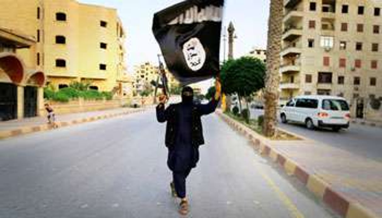 À Racca, en Syrie, un jeune combattant brandit le drapeau de l’État islamique. © Reuters/Stringer