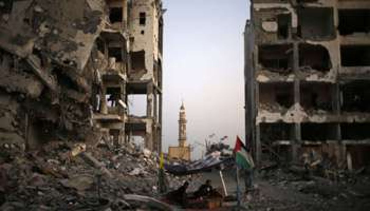 Des Palestiniens devant des immeubles détruits dans la bande de Gaza. © Reuters