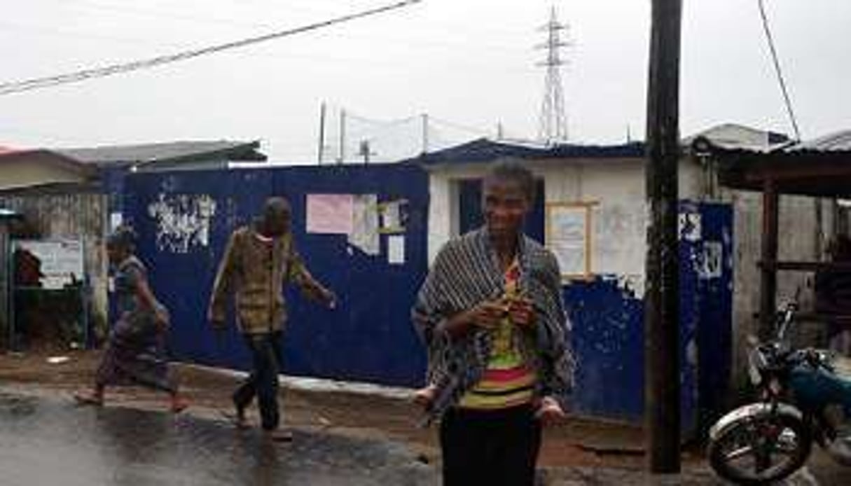 Des passants devant l’école qui sert de centre d’isolement des malades d’Ebola. © AFP