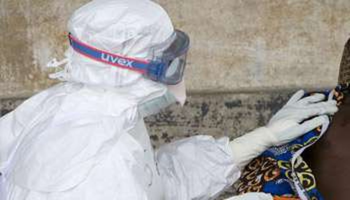 Un infimier en combinaison de protection s’occupe d’un patient infecté par le virus Ebola en RDC. © Christopher Black/AFP