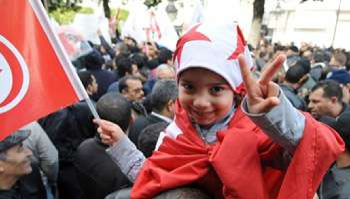 Des Tunisiens célèbrant la chute de Ben Ali, le 14 janvier 2012. © Fethi Belaid/AFP