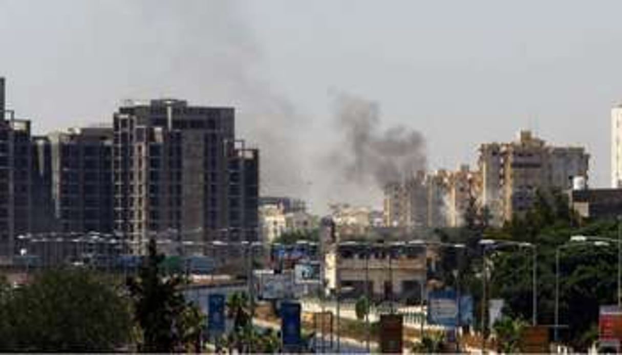 Une colonne de fumée s’élève au-dessus de la route de l’aéroport de Tripoli, en juillet 2014. © Mahmud Turkia/AFP