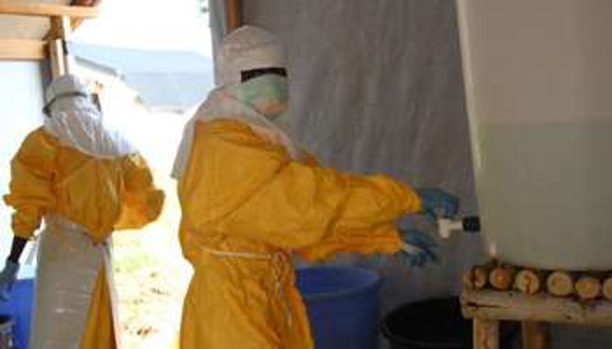 Des agents sanitaires désinfectent des toilettes dans un centre de traitement Ebola, en RDC. © AFP