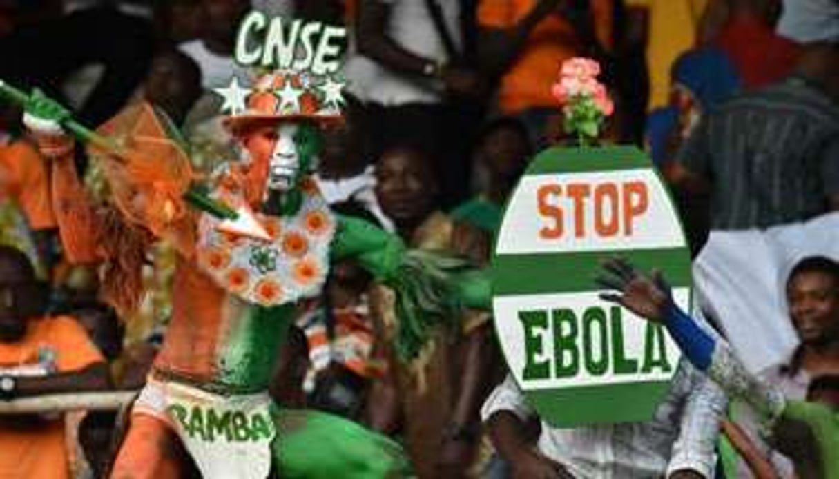 Des supporteurs brandissant un panneau Stop Ebola. © AFP