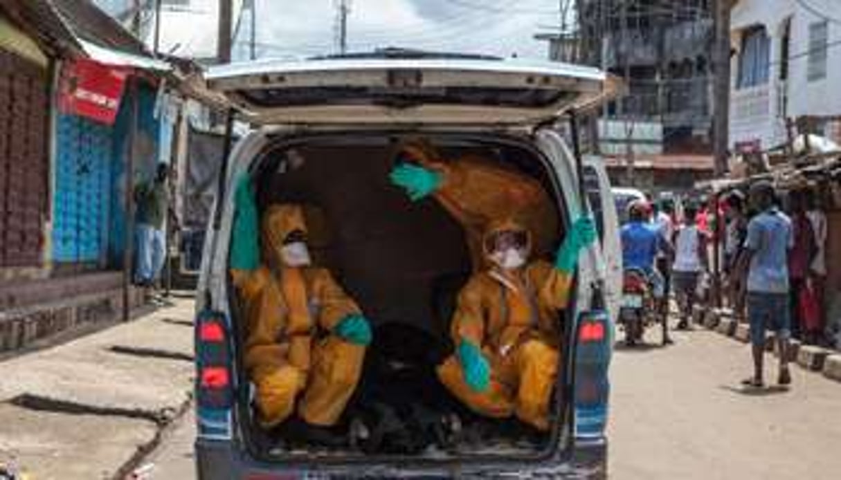 Des volontaires ramassent les corps de victimes d’Ebola à Freetown, le 8 octobre 2014. © AFP