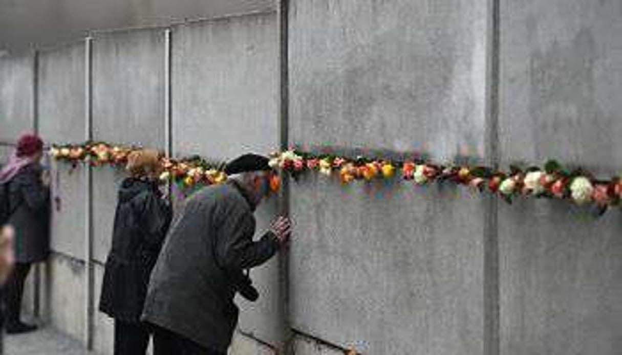 Des visiteurs regardent à travers les fentes d’un morceau de l’ancien Mur, le 9 novembre 2014. © AFP