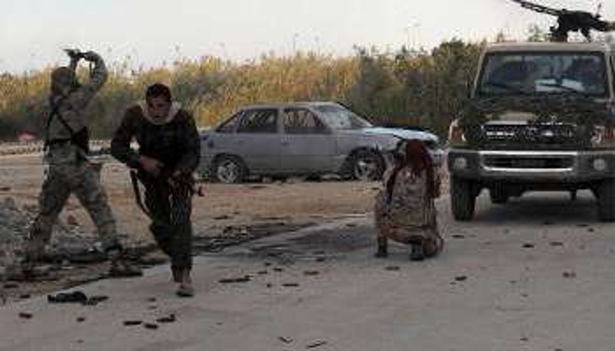 Des membres des forces armées libyennes tirent en direction de milices islamistes. © AFP