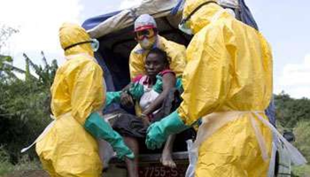 Du personnel de la Croix Rouge française transport un malade atteint par Ebola, en Guinée. © AFP