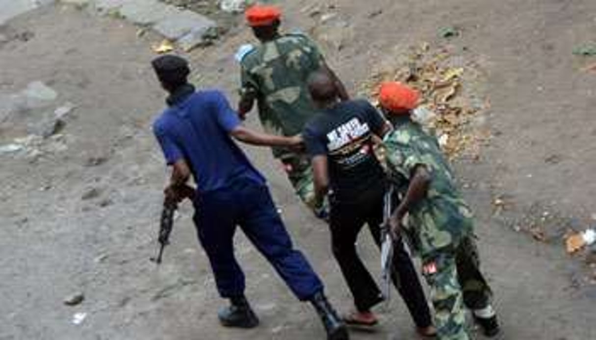 Des policiers emmènent un manifestant, le 19 janvier 2015 à Kinshasa, en RDC. © AFP