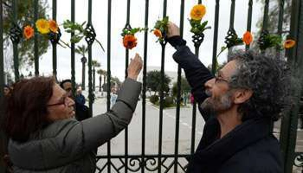 Des Tunisiens accrochent des fleurs sur les grilles du musée du Bardo à Tunis, 24 mars 2015. © Fadel Senna/AFP