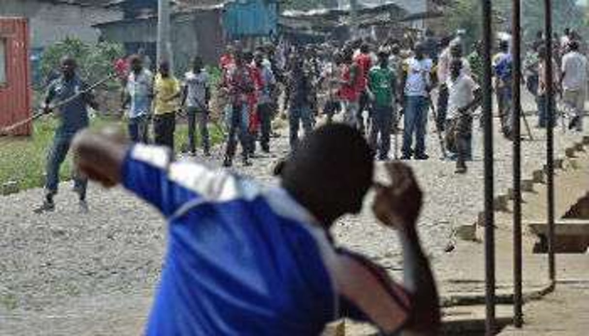 Un manifestant lance une pierre en direction de membres de la jeunesse du parti au pouvoir, à Bujum © Carl de Souza/AFP