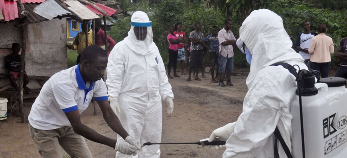 Des professionnels de la santé se désinfectent après  avoir fait des tests sanguins dans le village du Liberia où l’adolescent est mort de l’épidémie le 30 juin 2015. © Abbas Dulleh/AP/SIPA