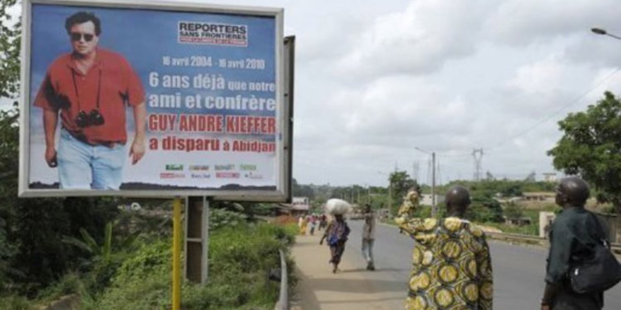 Des Ivoiriens regardent, le 15 avril 2010, une affiche montrant Guy-André Kieffer, disparu à Abidjan le 16 avril 2004. © Issouf Sanogo/AFP