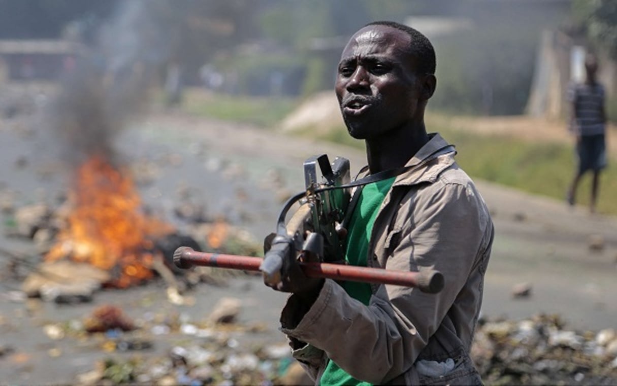 Un manifestant pointe une fausse arme vers des soldats lors d’une manifestation à Bujumbura en juin 2015. © Gildas Ngingo/AP/Sipa