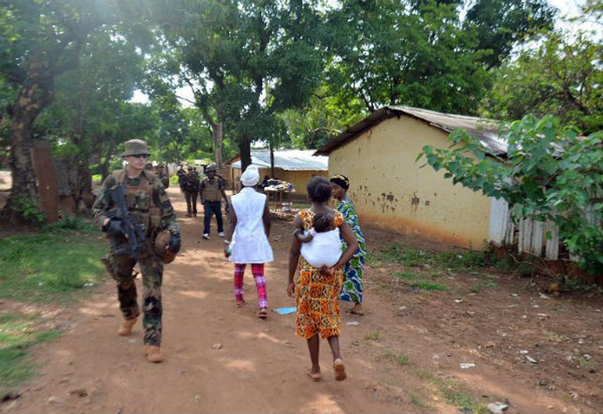 Une centrafricaine portant un bébé passe devant des soldats français de l’opération Sangaris en patrouille à Bangui le 20 mai 2015. © Patrick Fort/AFP