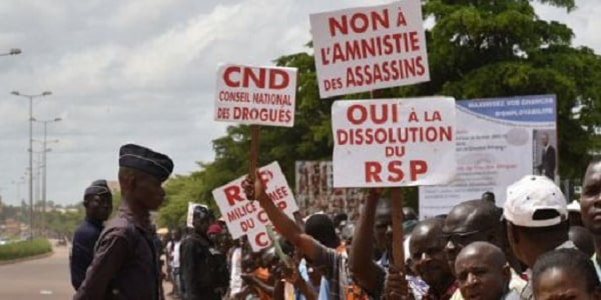 Des manifestants brandissent des pancartes le 23 septembre 2015, à Ouagadougou, non loin de l’hôtel qui accueille les chefs d’Etat de la Communauté des Etats de l’Afrique de l’Ouest (Cédéao), organisation sous-régionale qui assure la médiation dans la crise burkinabè. © Sia Kambou/AFP