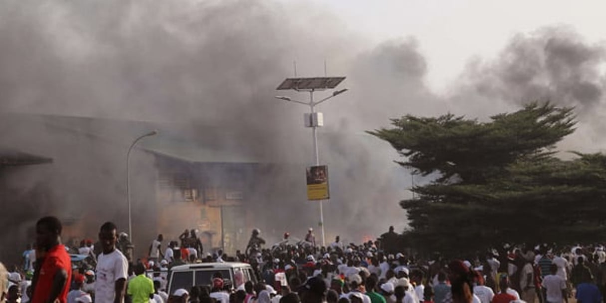 À Conakry, de la fumée s’échappe d’un marché à côté d’un rassemblement de l’UFDG, en 2015. © Youssouf Bah/AP/SIPA