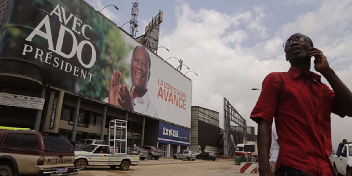 Un Ivoirien près d’une affiche de campagne XXL d’Alassane Ouattara, le 21 octobre à Abidjan. © Schalk van Zuydam/AP/SIPA