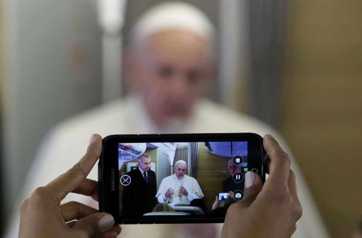 Un journaliste filme avec son téléphone le pape François à bord de l’avion qui le conduit au Kenya, le 25 novembre 2015. © Andrew Medichini/AP/SIPA