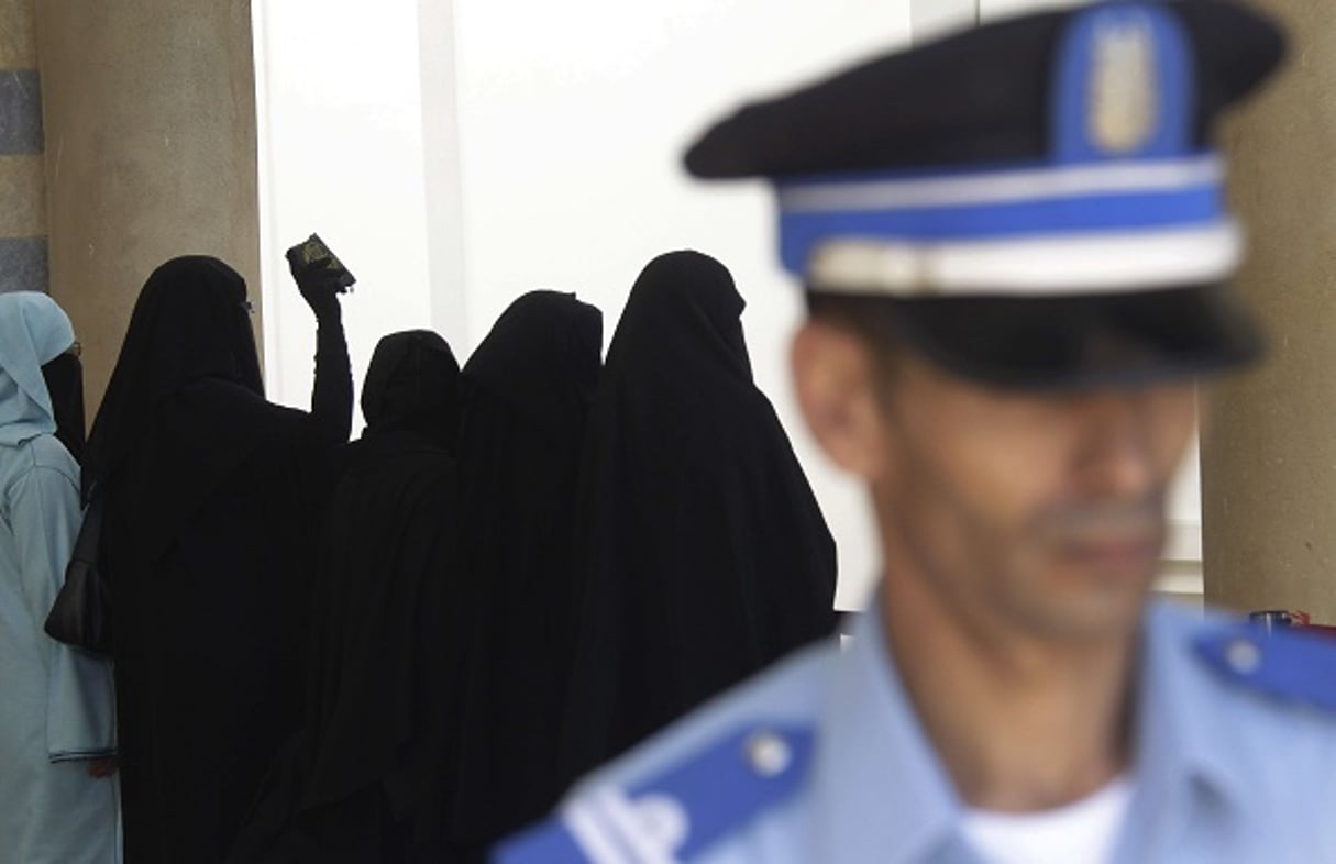 Un officier de police devant des proches des suspects dans l’affaire de l’attentat du café Argana, près de Rabat, le 6 octobre 2011.