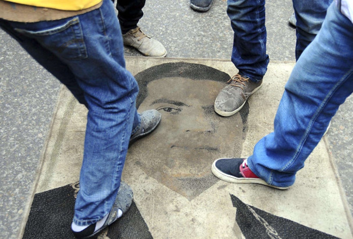 Des tunisiens piétinant le portrait de Ben Ali lors d’une manifestation le 14 janvier 2014. © Hassene Dridi/AP/SIPA