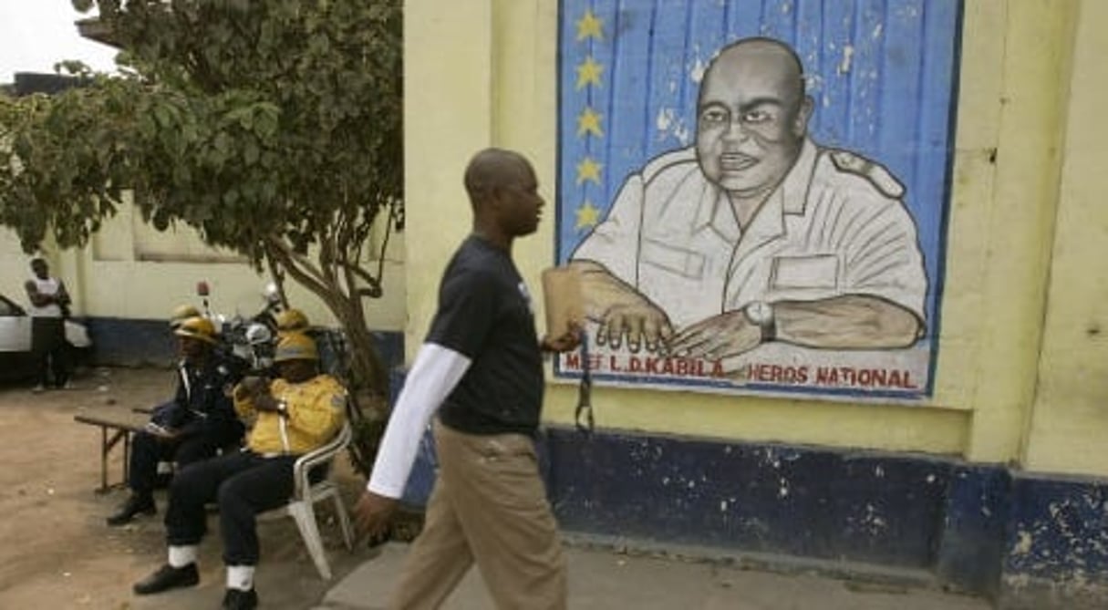 Un Cogolais passe devant un portrait mural de Lauren-Désiré Kabila, le 9 août 20016 à KInshasa. © MICHEL EULER / AP / SIPA