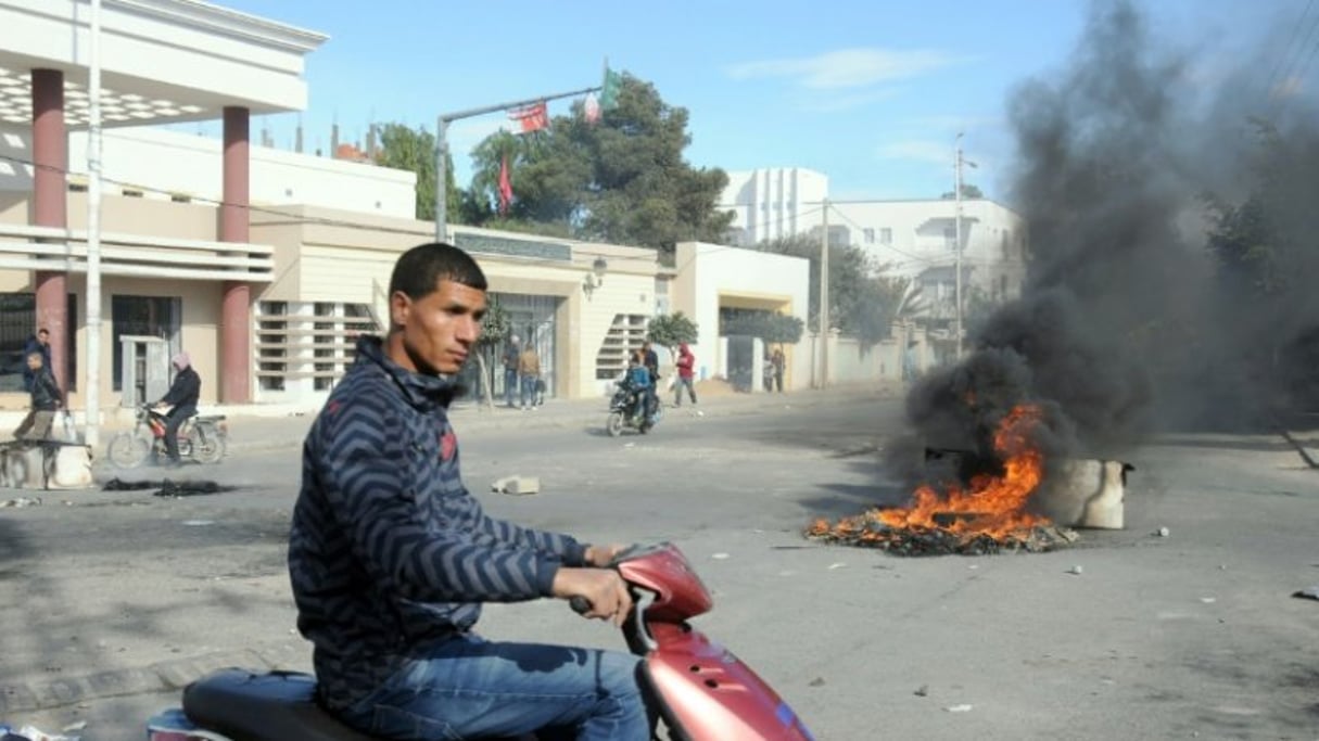 Un jeune Tunisien passe devant des pneus brûlés lors de heurts avec la police, le 20 janvier 2016 à Kasserine. © AFP