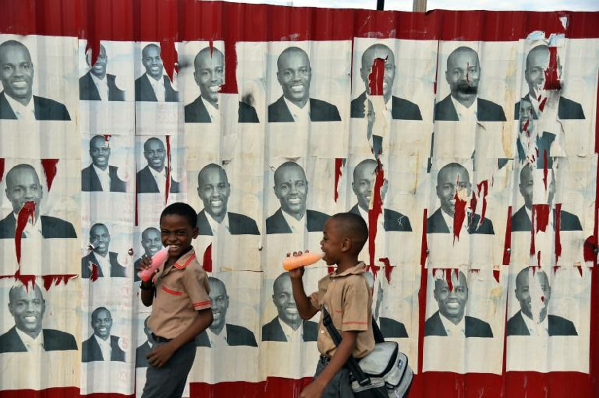 Des écoliers haïtiens passent devant des affiches électorales du candidat à la présidentielle Jovenel Moise, le 21 janvier 2016 à Port-au-Prince. © Hector Retamal/AFP