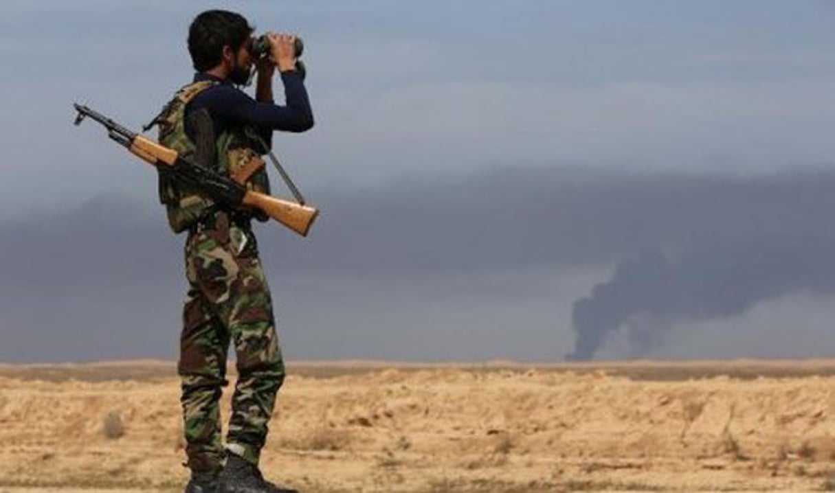 Un combattant kurde observe la bataille contre les forces du groupe Etat islamique près de Tikrit, en Irak, le 8 mars 2015 © Ahmad Al-Rubaye/AFP