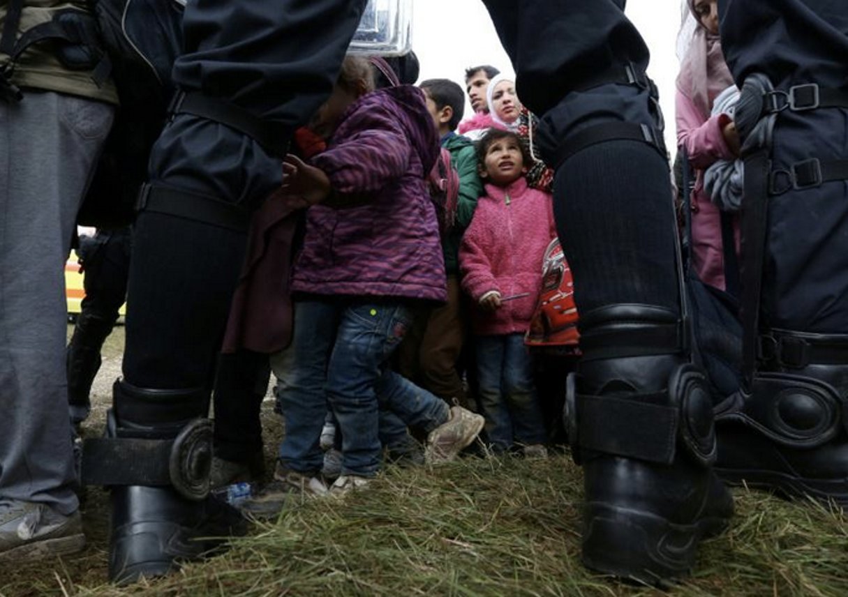 Des enfants parmi les migrants sont encadrés par des policiers slovènes, le 22 octobre 2015 près du village de Rigonce en Slovénie. © Stringer/AFP