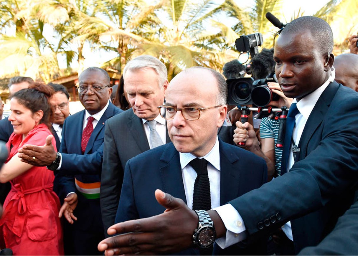 De g. à dr., Georges Philippe Ezaley, le maire de Grand-Bassam, accueillant Jean-Marc Ayrault et Bernard Cazeneuve, le 15 mars. © ISSOUF SANOGO/AFP