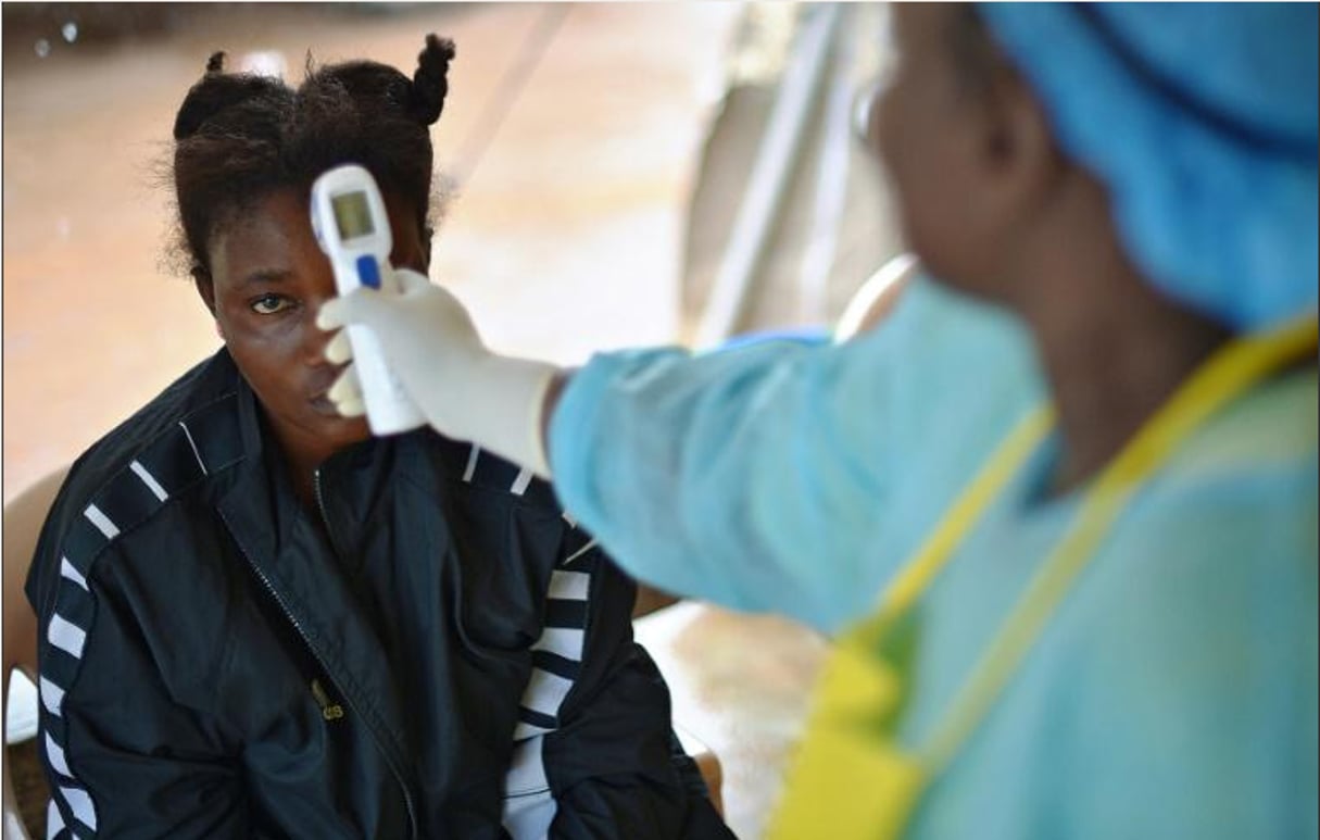 Prise de température d’une petite fille potentiellement porteuse du virus Ebola en Sierra Léone © Carl de Souza/ AFP