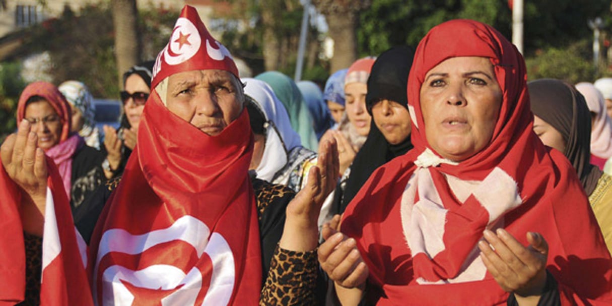 Des Tunisiennes voilées du drapeau national prient devant la mosquée Zitouna, à Tunis, le 8 août 2013. © Hassene Dridi / AP / SIPA