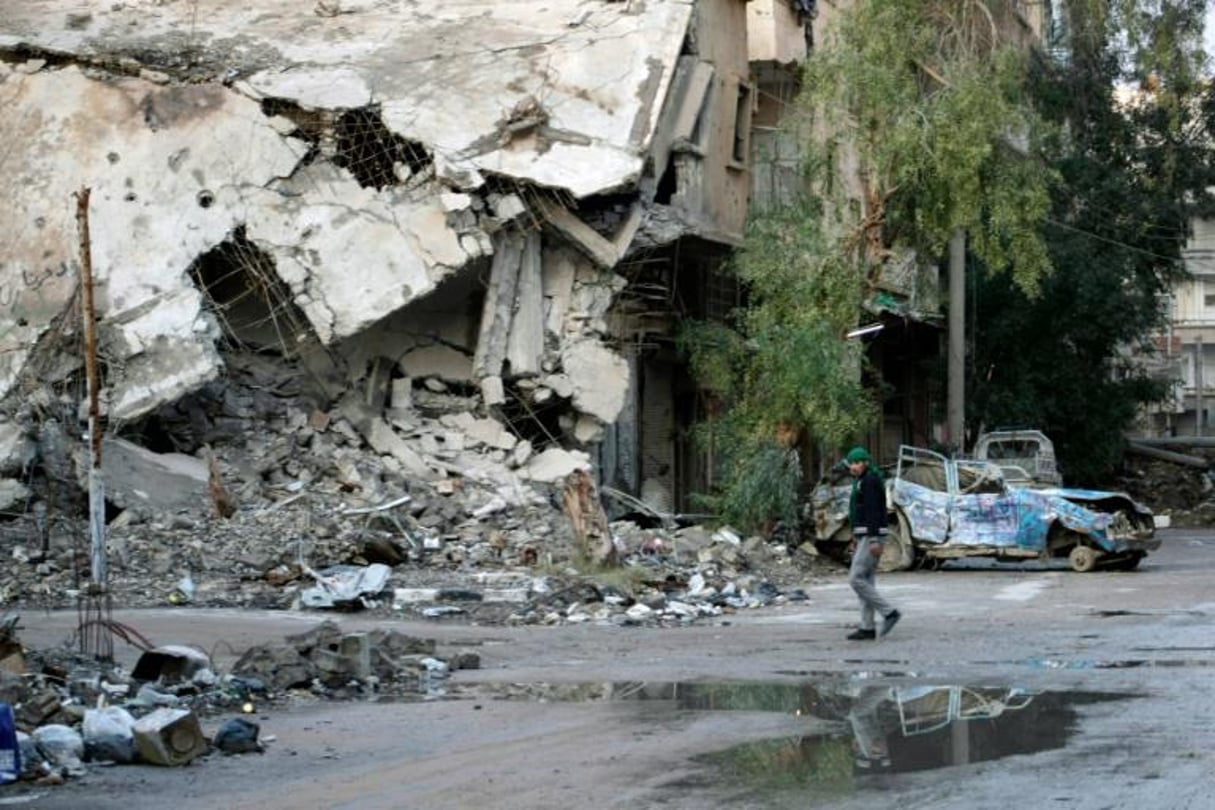 Un homme marche dans une rue détruite de la ville syrienne de Deir Ezzor, le 15 février 2014. © AFP