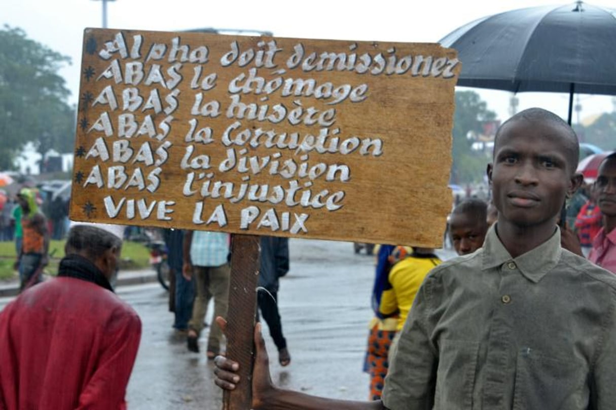 Un manifestant de l’opposition brandit une pancarte demandant la démission du président Alpha Condé, le 16 août 2016 à Conakry. © Cellou Binani/AFP