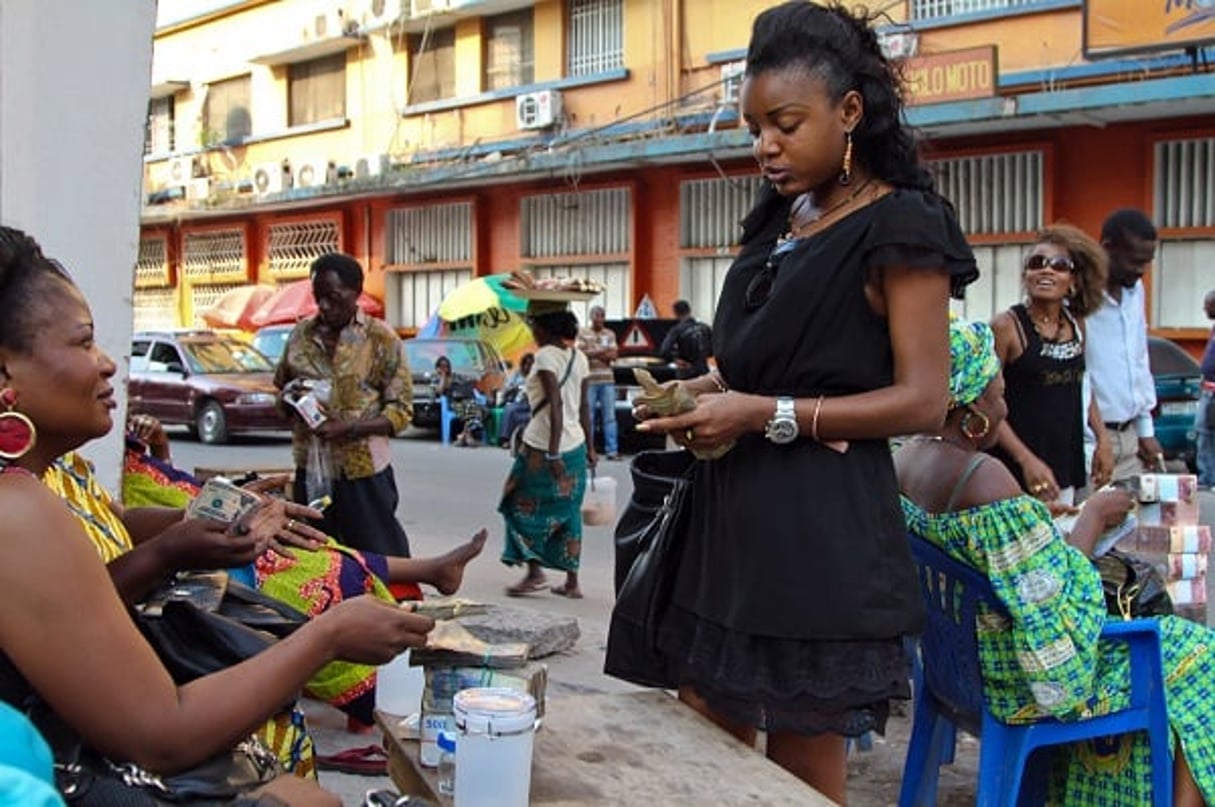 Une jeune fille échange des dollars en francs congolais à Kinshasa. © Baudouin Mouanda pour JA