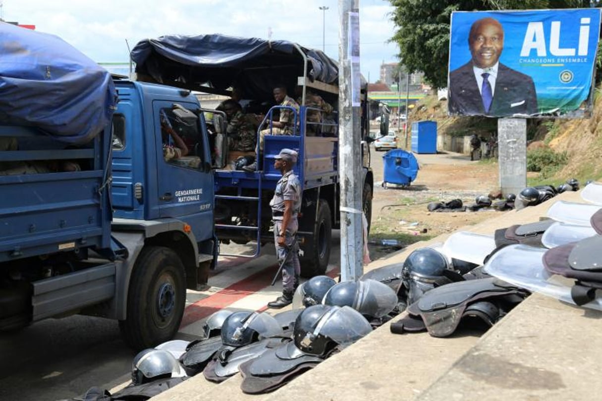 Des forces de sécurité gabonaises devant une affiche du président Ali bongo Ondimba à Libreville, le 23 septembre 2016. © Samir Tounsi/AFP