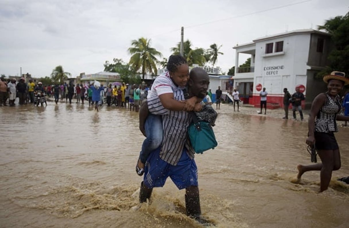 Un homme prête main-forte à une femme lors des inondations causées par l’ouragan Matthew, le 5 octobre 2016. © Dieu Nalio Chery/AP/SIPA