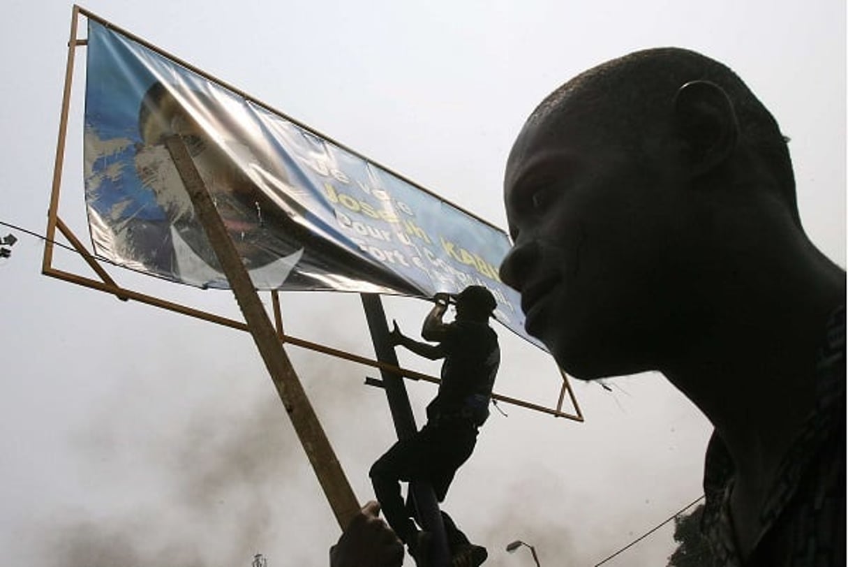 Des opposants retirent une affiche représentant Joseph Kabila, à Kinshasa, le 25 juillet 2006. © JEROME DELAY/AP/SIPA