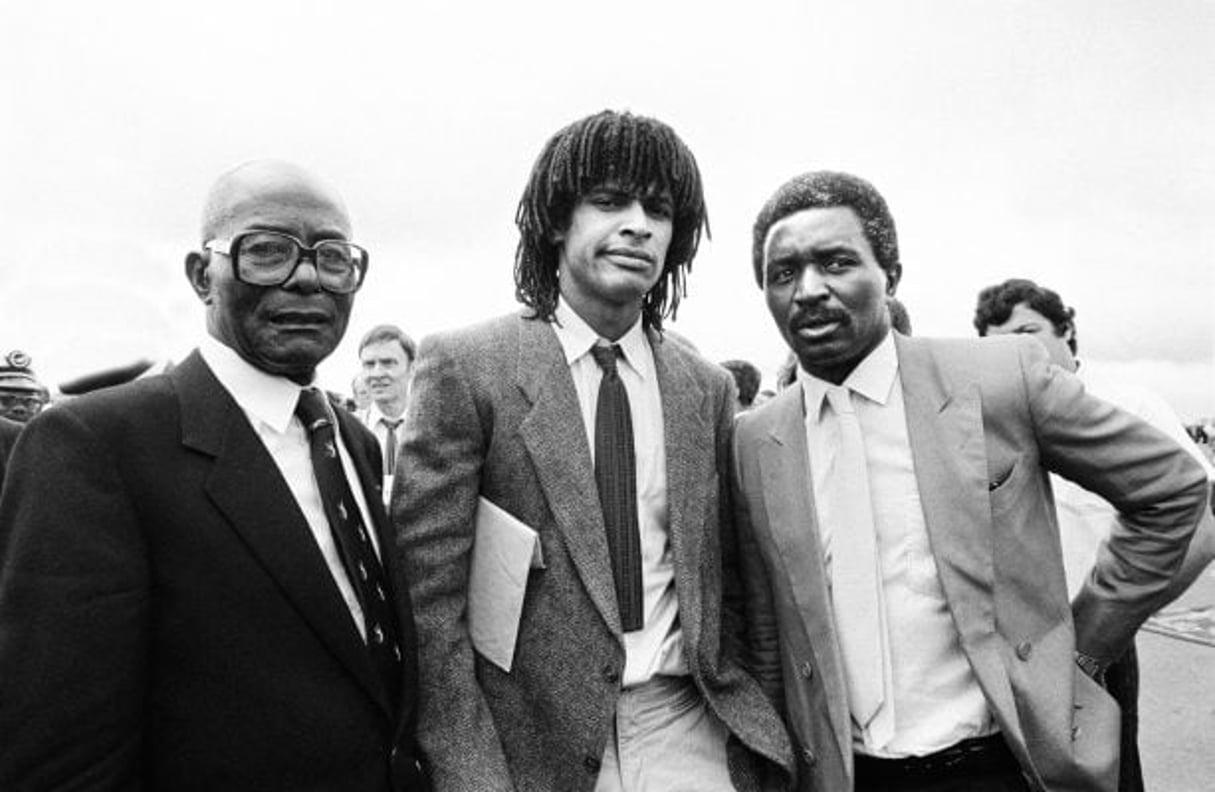 Cette photo du 20 juin 1983 montre le chanteur et joueur de tennis Yannick Noah (au centre) posant avec son père, l’ancien footballeur Zacharie Noah (à droite) et son grand-père Simon Noah (à gauche) à Yaoundé. © Pierre GUILLAUD/AFP