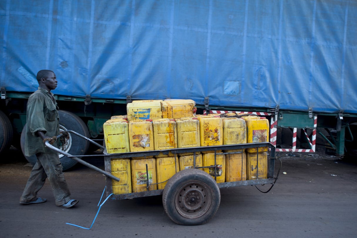 Un homme transporte des bidons d’huile de Palme.  Le 10 décembre 2012. Guinée Conakry. © Sylvain CHERKAOUI pour Jeune Afrique