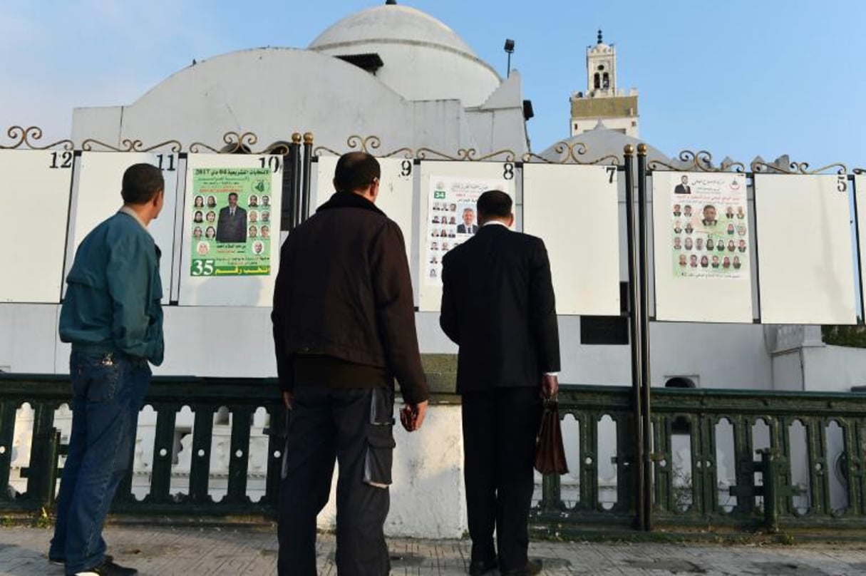 Des Algériens regardent les affiches électorales lors de la campagne pour les élections législatives, le 9 avril 2017 à Alger. © AFP