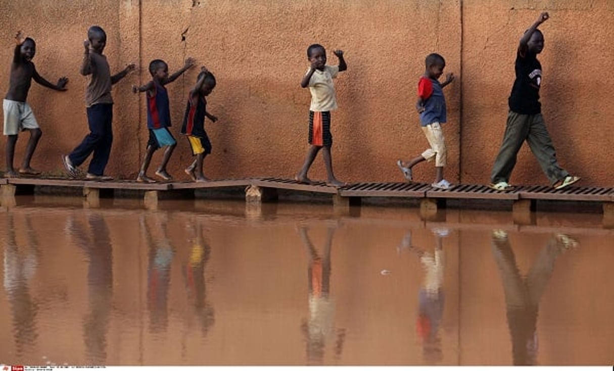 Des enfants marchant sur un trottoir de fortune dans une rue inondée de Niamey, le 2 août 2009. © REBECCA BLACKWELL/AP/SIPA